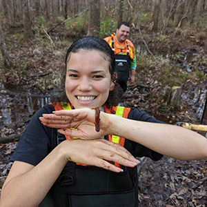 Stella Wilson holding a salamander in a forest wetland